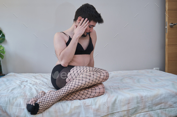 Young man wearing fishnet stockings and bra. stock photo NULLED