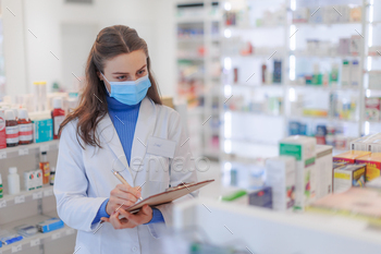 Young pharmacist checking medicine stock in pharmacy.