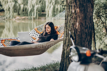 Freelancer working in the park while resting in hammock stock photo NULLED