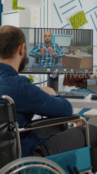 Immobilized freelancer talking on videocall with remote colleague stock photo NULLED
