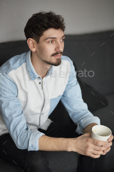 Freelancer resting with a cup of coffee on a couch while thinkin stock photo NULLED