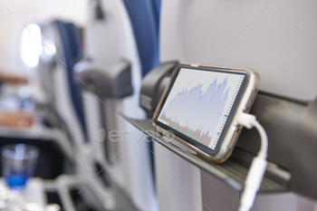Airplane cabin interior with smartphone with stock graphic values stock photo NULLED