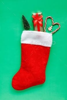 Christmas stocking with gift and decorations on green background. stock photo NULLED