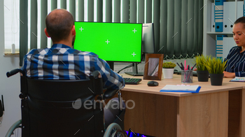 Disabled freelancer looking at pc with green screen stock photo NULLED