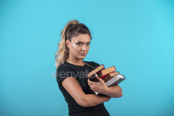 Female student holding a heavy stock of books stock photo NULLED