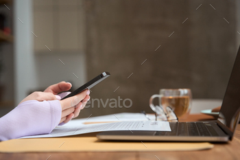 Freelancer using mobile phone and laptop indoors stock photo NULLED