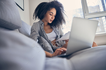 Girl freelancer working on her laptop on the sofa stock photo NULLED