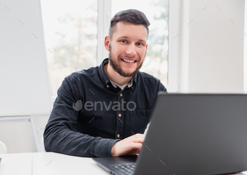 Happy male freelancer using laptop stock photo NULLED