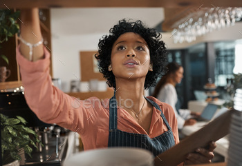 Shot of a woman counting stock while working in a cafe stock photo NULLED
