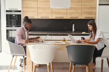 Two concentrated young freelancers sitting at laptops stock photo NULLED