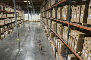 Warehouse worker checking inventory of stock on racks in a distribution warehouse. stock photo NULLED