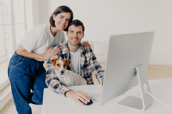 male freelancer works remotely at computer with dog stock photo NULLED